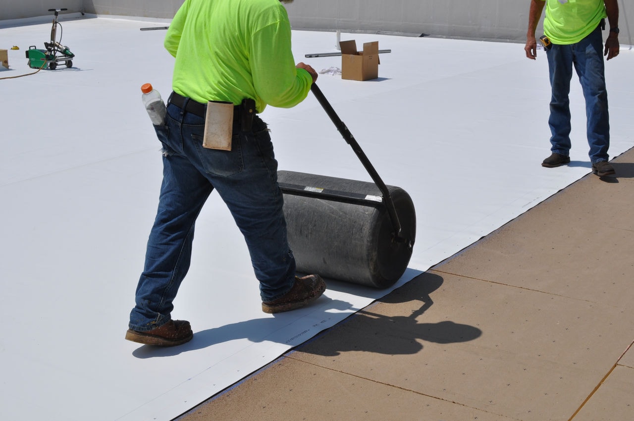 Workers applying membrane on low-slope roof.