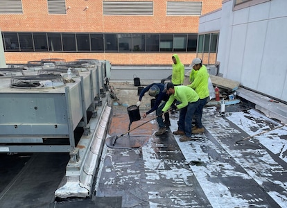 A team of roofers installing Hot-rubberized Asphalt Flashing on a commercial roof.