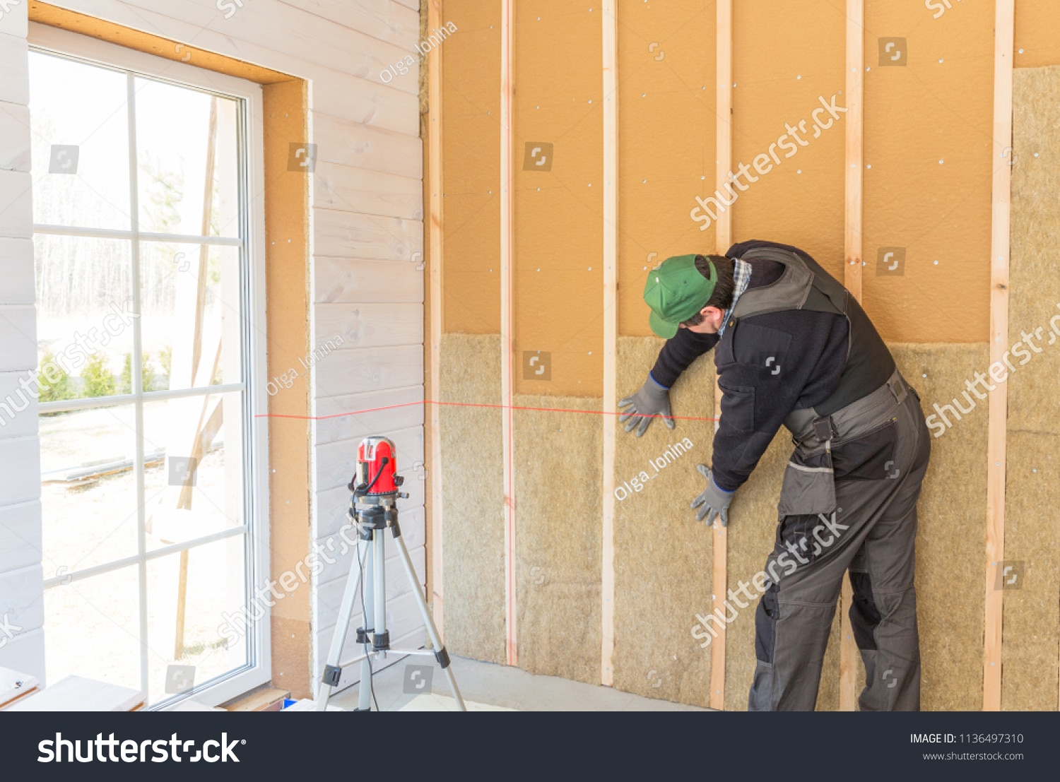 Construction worker thermally insulating wood-frame house.