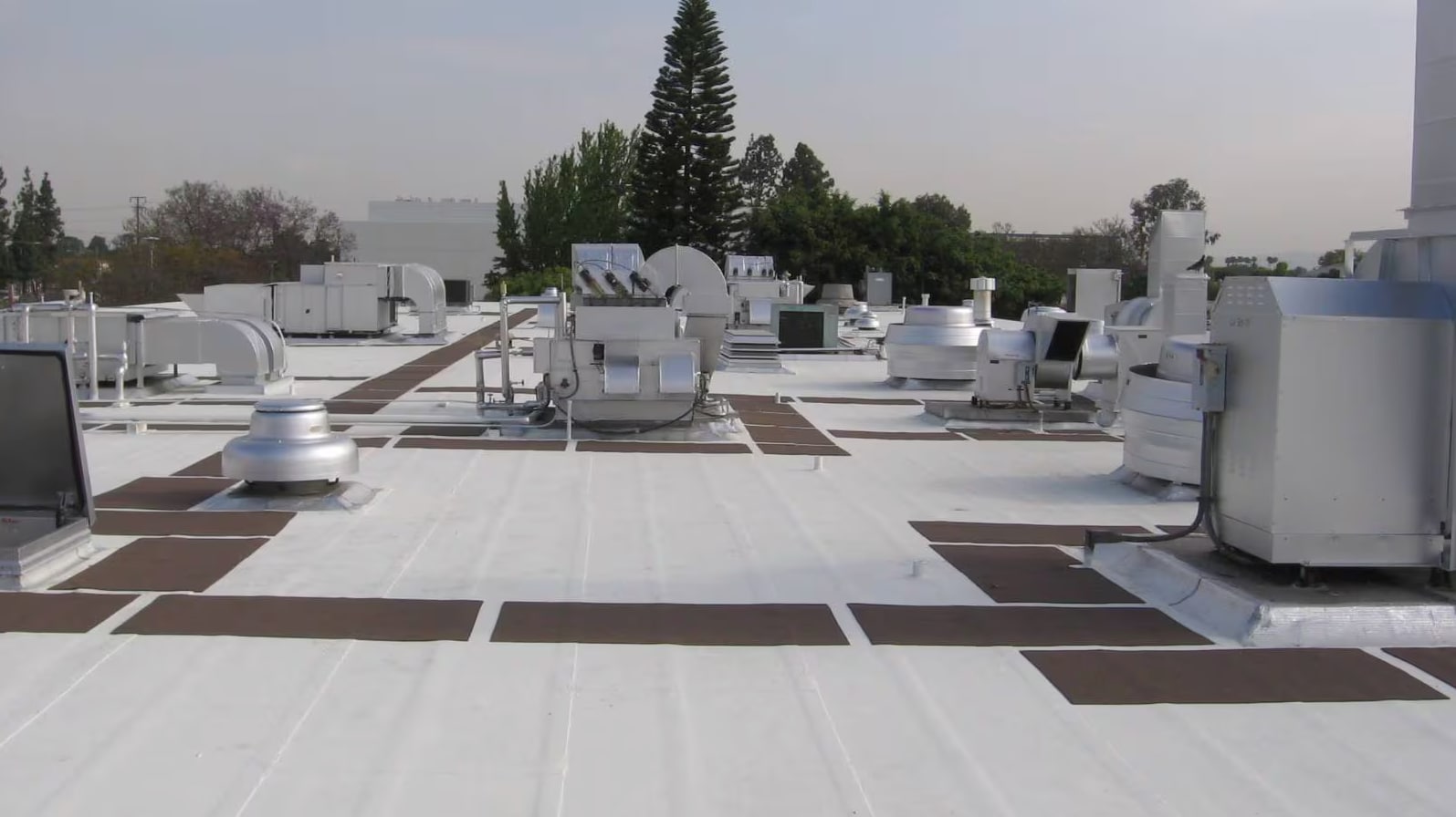 A commercial building rooftop with several ventilation systems.