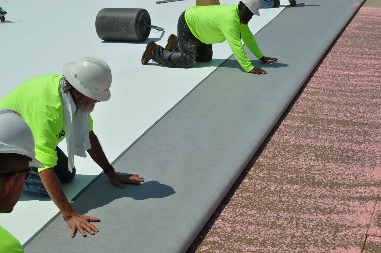 Rolls of PVC roofing membrane being installed