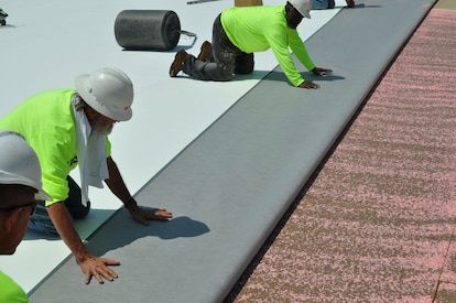 Rolls of PVC roofing membrane being installed