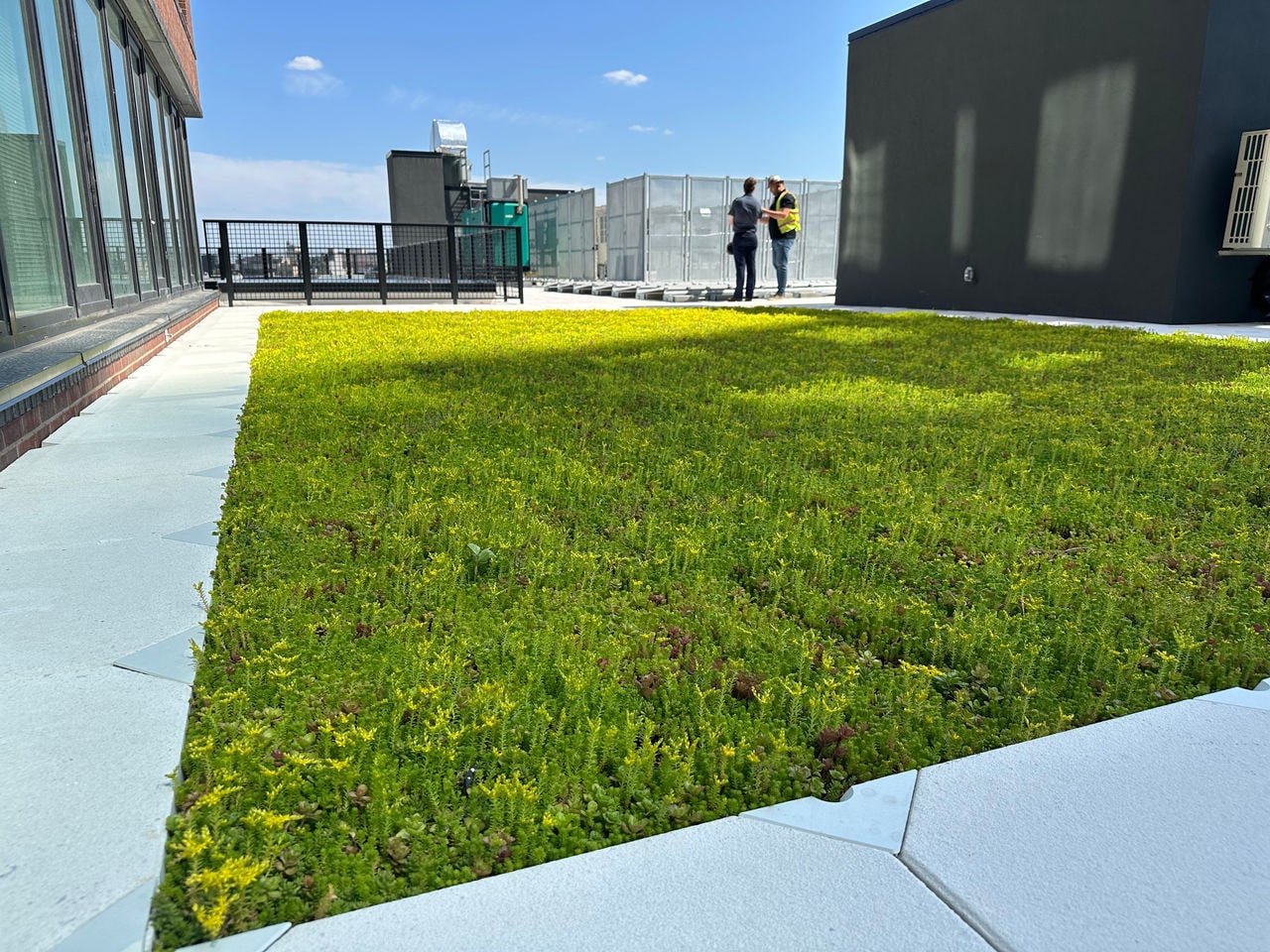 Two people look at a finished roof on a high-rise building