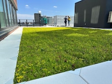 Two people look at a finished roof on a high-rise building